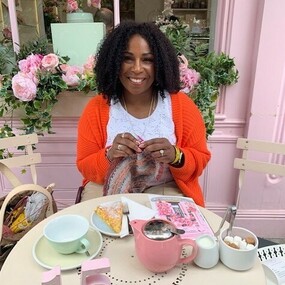Cecilia Nelson-Hurt knits a shawl at a table set for tea in London