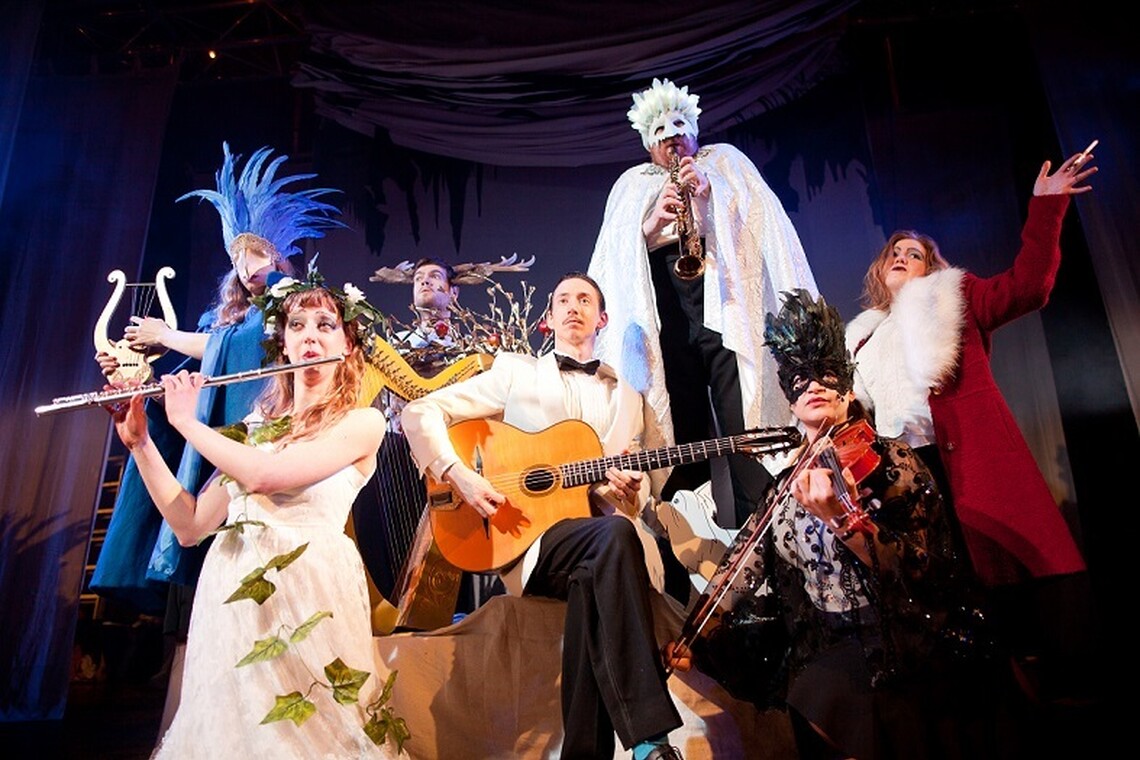 Seven musicians, seated and standing, in cabaret style clothing
