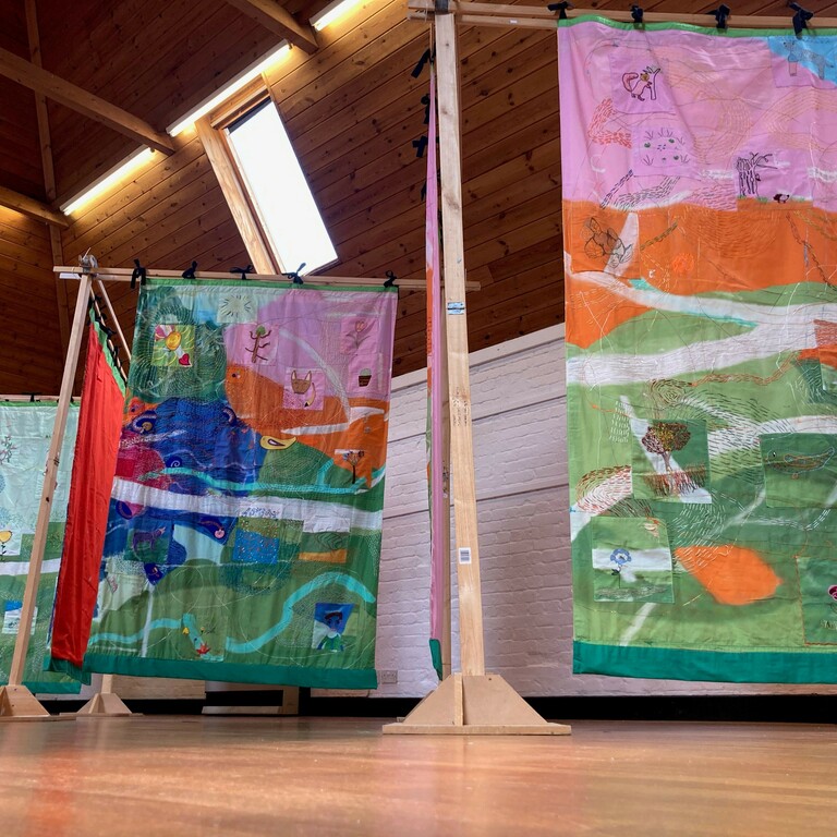 A large studio in farnham maltings with multi media murals hanging from the beams