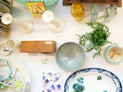 flat lay of lots of items on a table cards plates candle sticks ceramics glass bottles plant