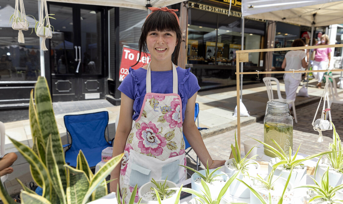 A woman smiles at a plant craft stall for Les Petites Plantes