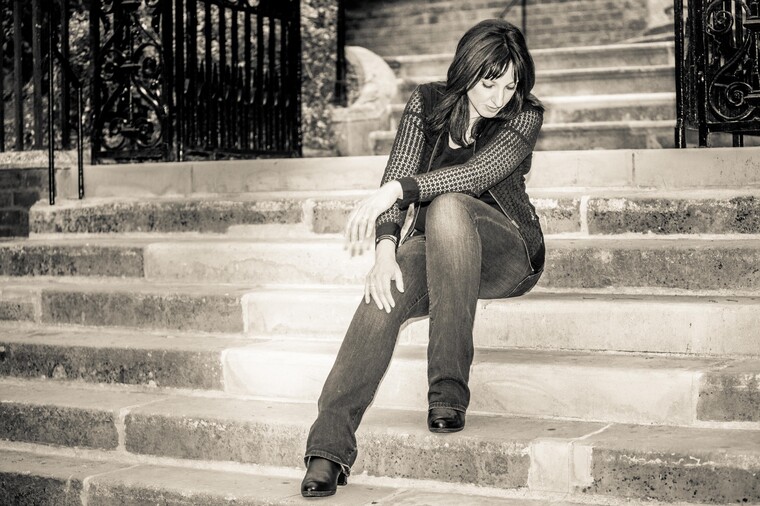 A black and white photo of Anna Neale sat on steps