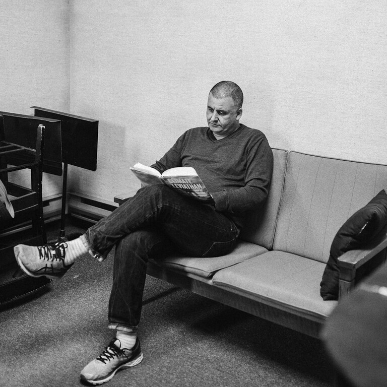 Black and white image of a man sitting on a chair reading a book