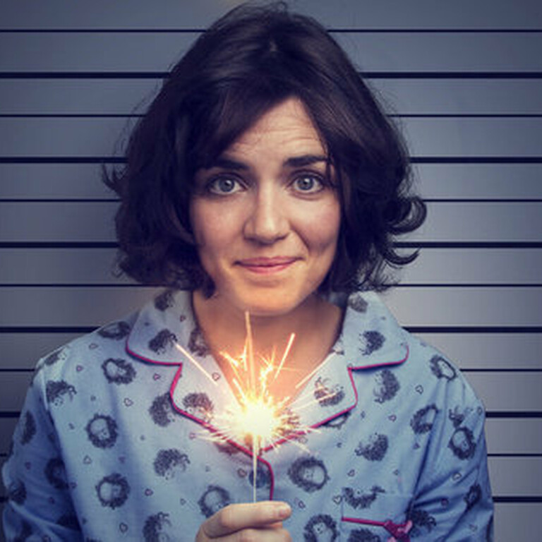 A white woman with short brown hair holding a lit sparkler