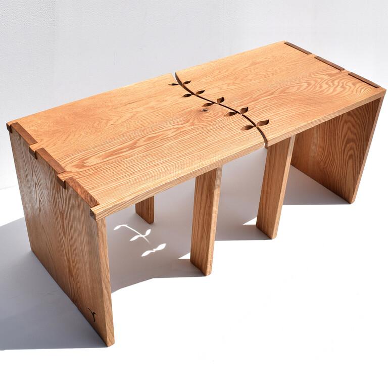A wooden table with a split leaf design running through the top