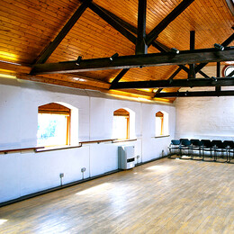 Empty sunlit room with wooden floor and vaulted ceiling
