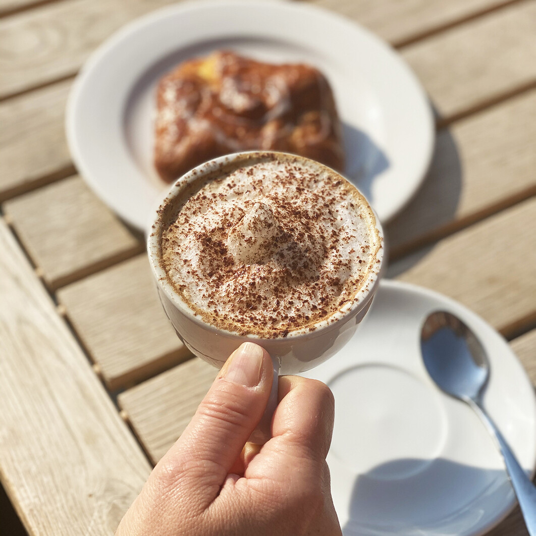 Shot of a hand holding a coffee at a table outside
