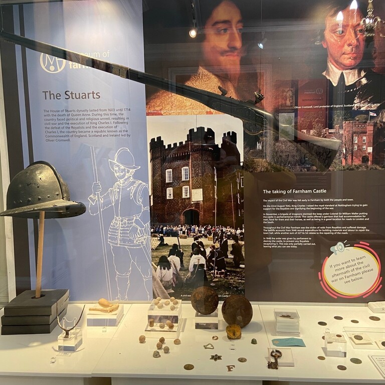 A display case showing artifacts of The Stuarts and information about Farnham castle.