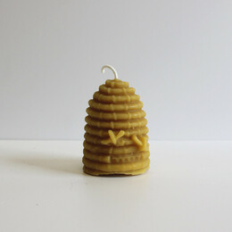 A small bee hive shaped candle on a white table