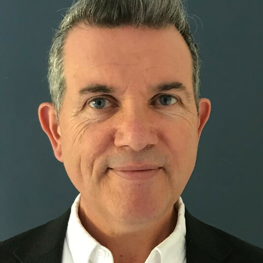 A middle-aged man with short dark hair wearing a white shirt