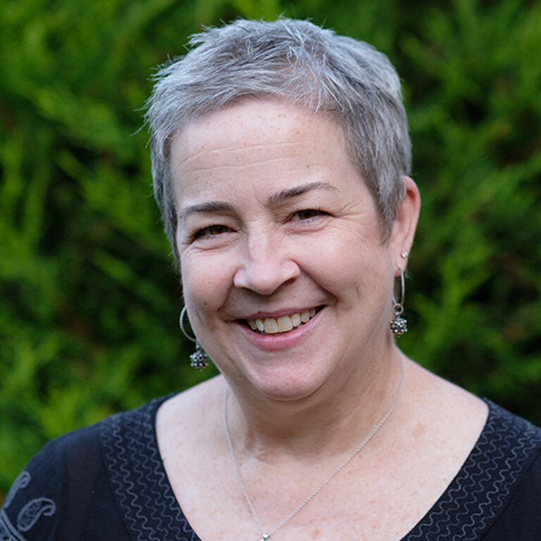 Photo of a woman outside, smiling.