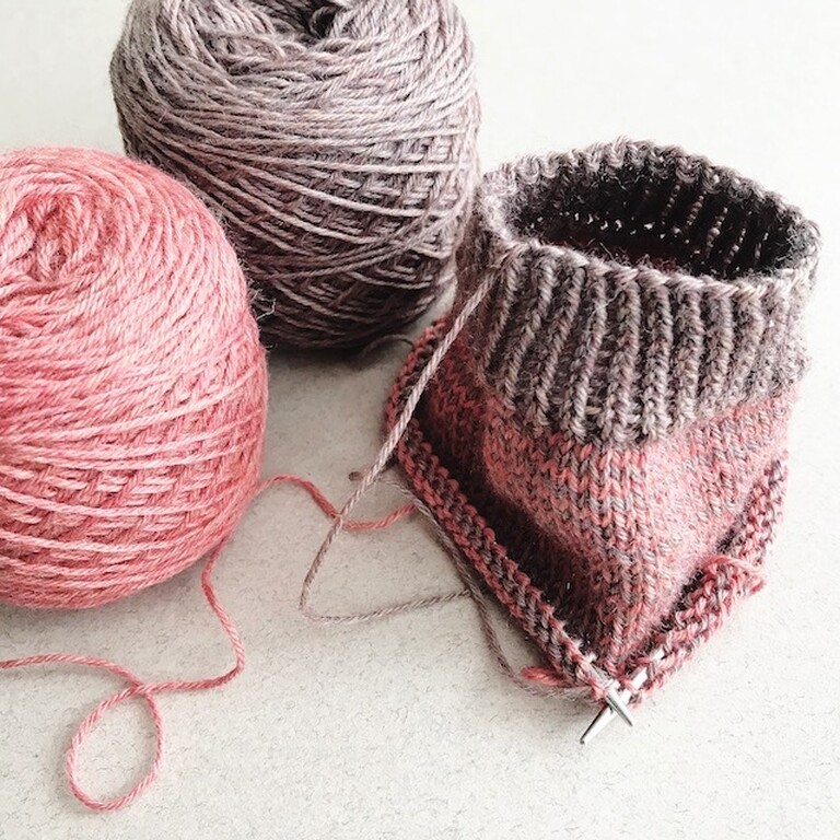 Two yarn balls and the beginnings of a knitted sock