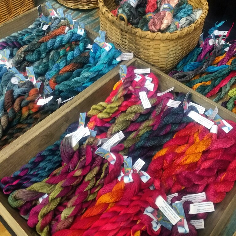 A selection of brightly coloured dyed yarn in boxes and baskets