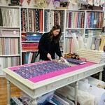 Illustration of two reels of thread, one on it side with the words Sew Creative, Petersfield on the bottom. Needle threaded through the other reel of thread which is upright