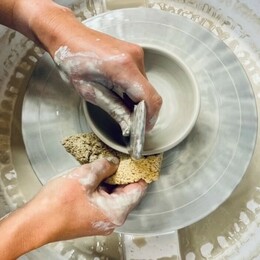 A pair of hands mould a clay pot