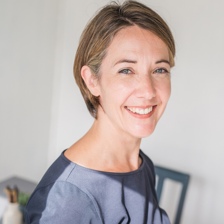 A smiling Woman named Nyree is wearing a dark blue long sleeved blouse.