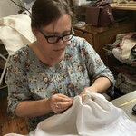 Alice from 'Ginny and Alice - Sewcialise workshop' sewing white fabric in a studio