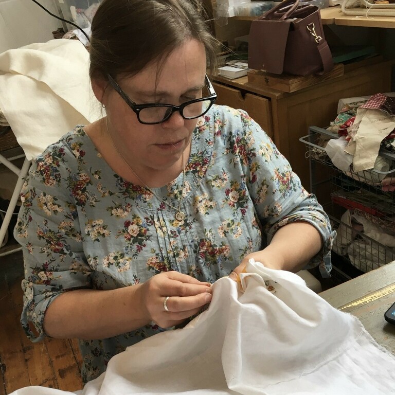 Alice from 'Ginny and Alice - Sewcialise workshop' sewing white fabric in a studio