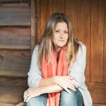 A photo of a lady sitting down in front of a wooden door