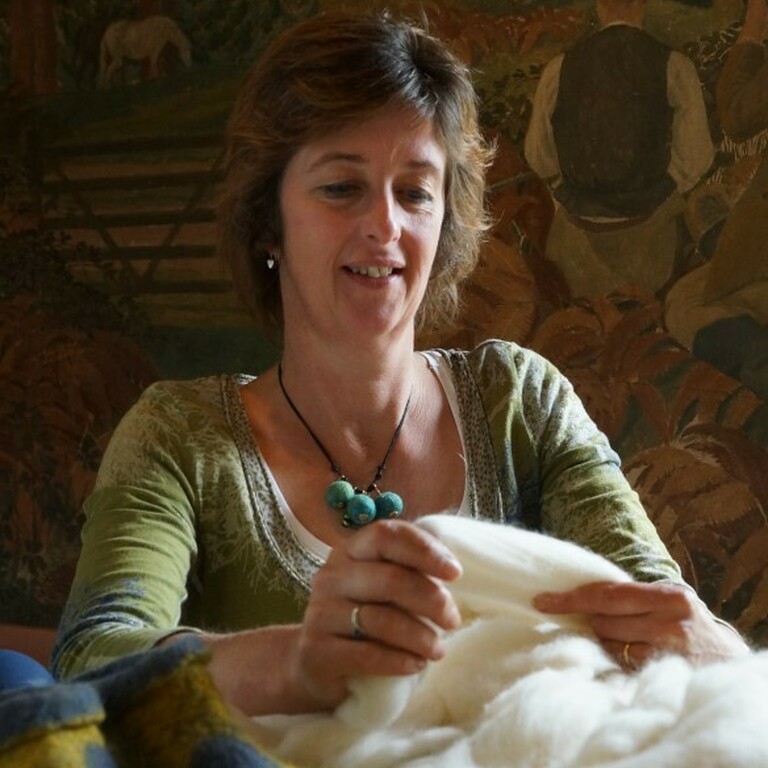 A woman sat at a table holding fabric.