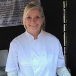 Photo of Coral Turan wearing a chef's jacket smiling.