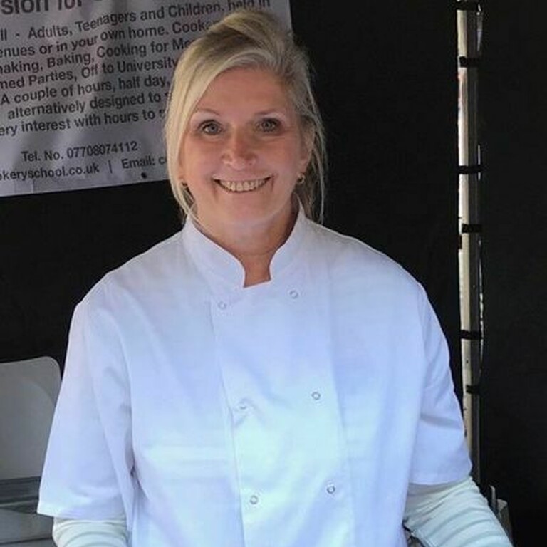 Photo of Coral Turan wearing a chef's jacket smiling.