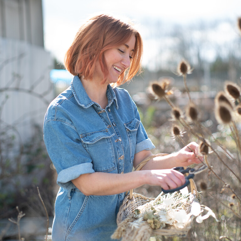 Lucy Rayner collecting plant clippings in a field