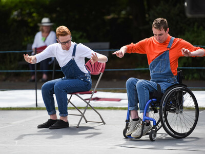 A man using a wheelchair and a man in a seat dance on stage in farnham gostrey meadows.