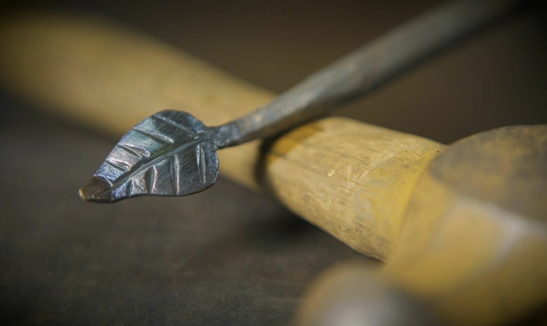 A silver metal rod with a small leaf design on the end