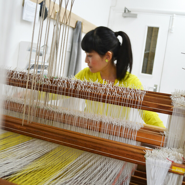 Nao Fukumoto using a weaving machine in a farnham maltings studio.