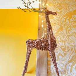 A woven willow Reindeer sculpture with fairy lights around it.