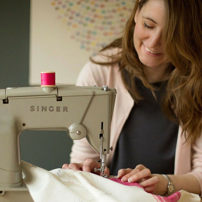 A photo of textiles tutor Lucy Nichols sitting in front of her sewing machine