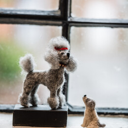 two hand-felted dogs, a large grey poodle with red headband and small white dog looking up at his pal