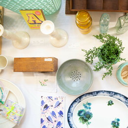 flat lay of lots of items on a table cards plates candle sticks ceramics glass bottles plant