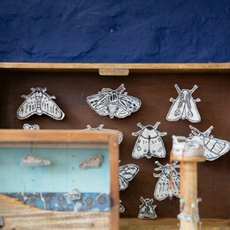 A craft stall display showing various layered illustrations and stitched images.