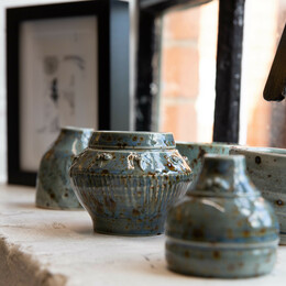 A table display of grey pottery bowls and jugs
