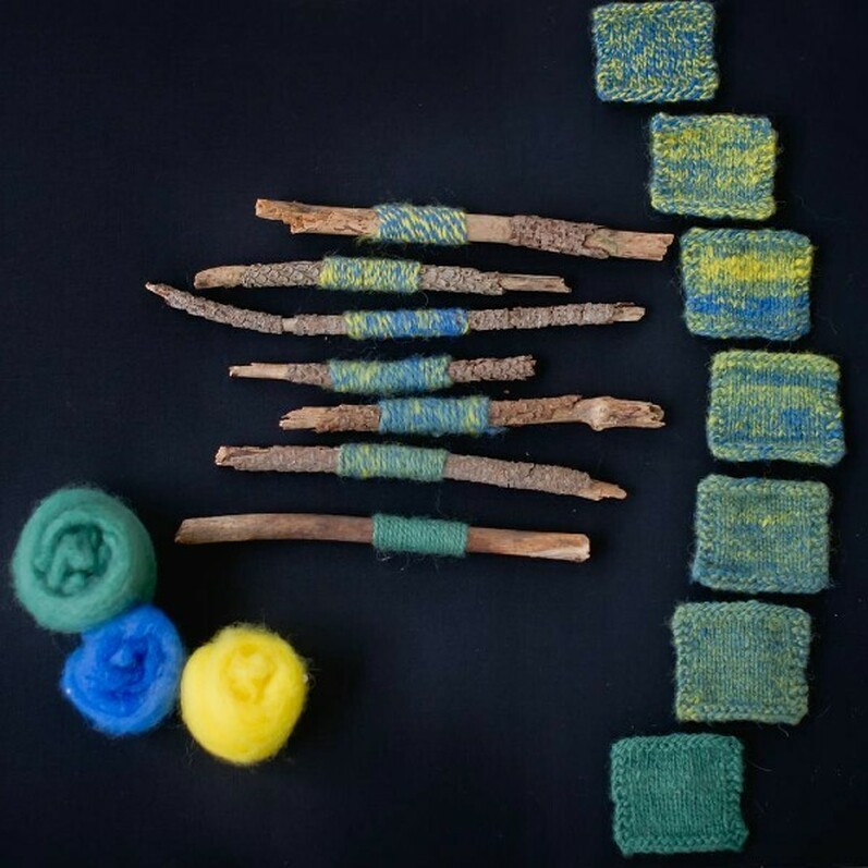 Three rounds of wool next to a collection of sticks with wool wrapped around them and a selection of colourful squares.