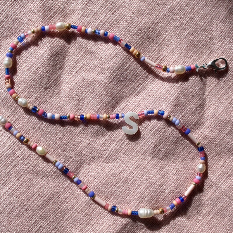 A photo of a beaded necklace laid out on a piece of fabric