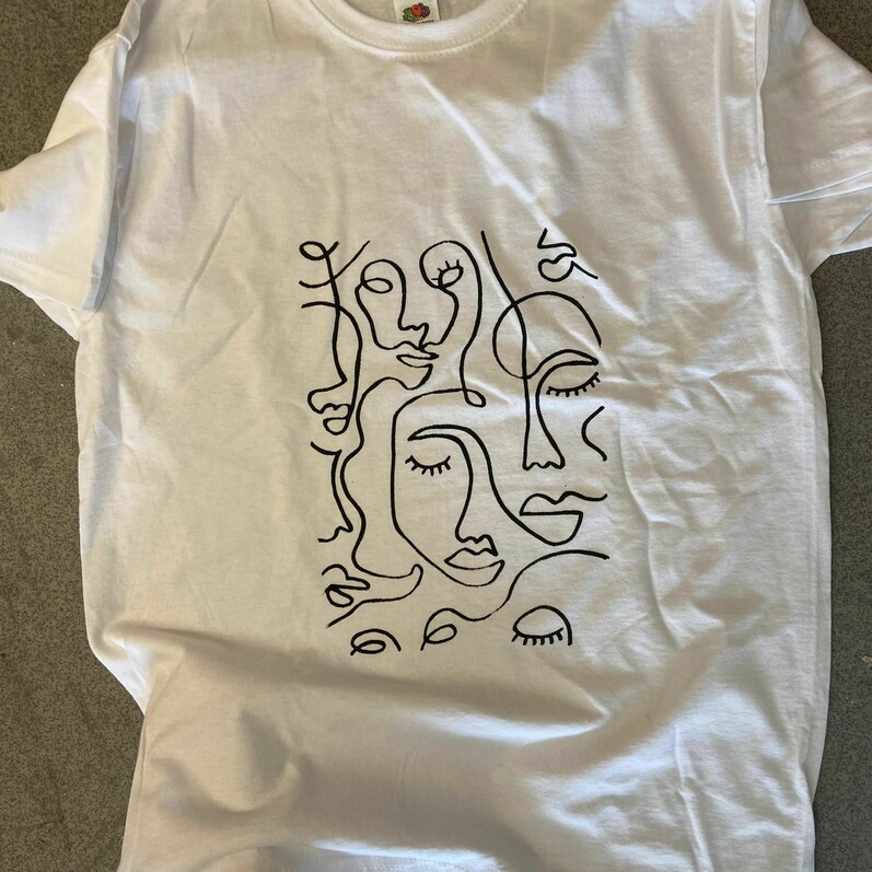 A photo of a white t-shirt that has an abstract design created from the process of screen printing