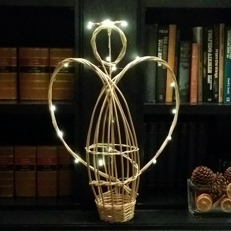A willow angel sculpture with fairy lights around it.