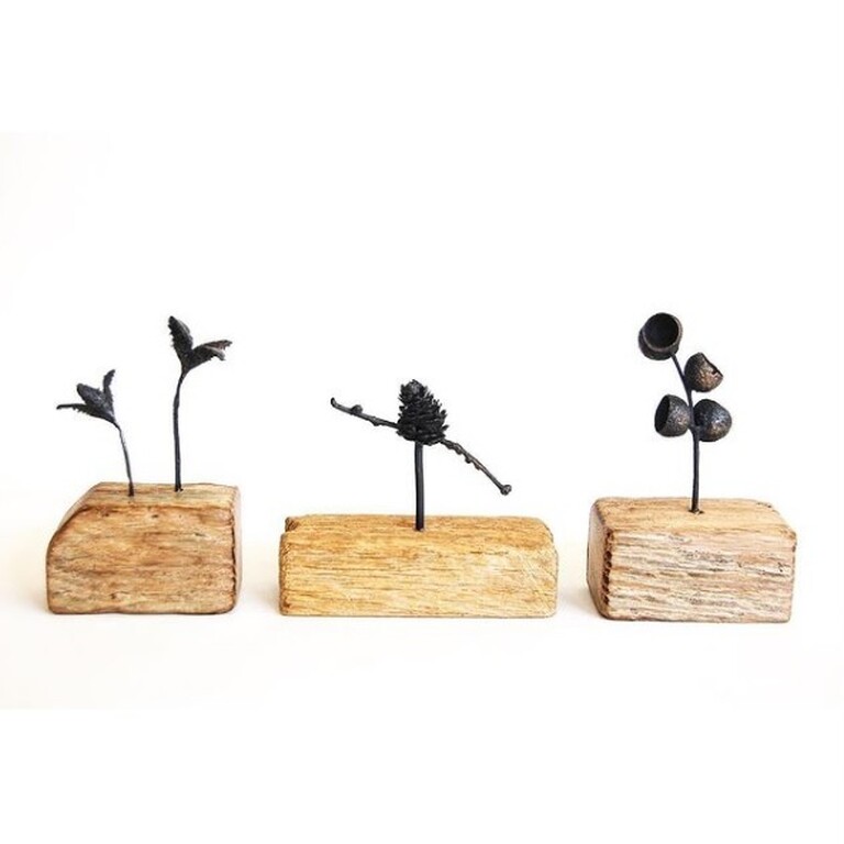 A trio of Wooden Base Sculptures with stick sprigs coming out of them.