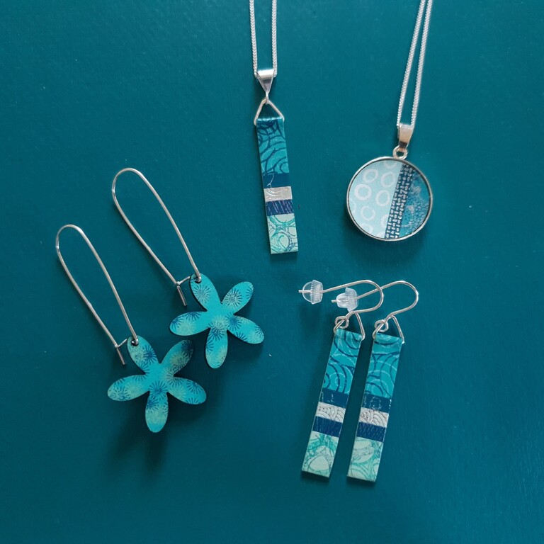 A blue background with a selection of blue earrings and necklaces by Circle and Dash