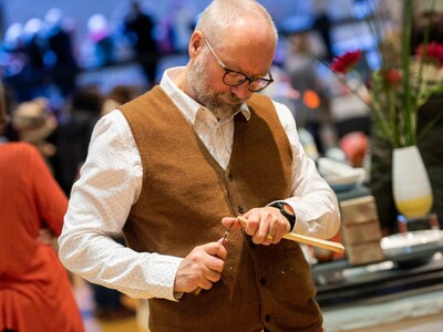 A man whittling a wooden spoon at the Festival of crafts