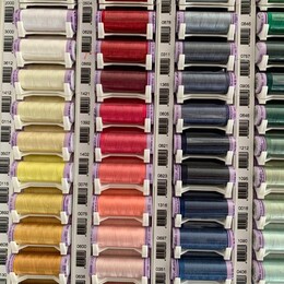 Three colourful rows of thread spools.