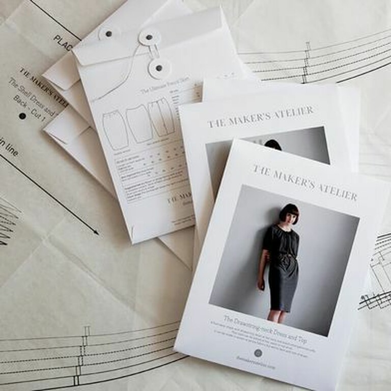 5 garment pattered packages strewn across a table with paper patterns opened behind them