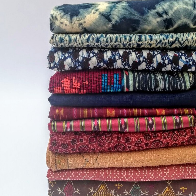 ten folded fabrics in a ples earthy reds brown and indigo colours and patterns
