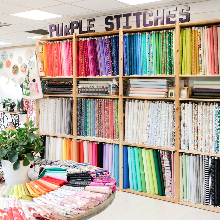 Purple stitches fabrics shop display with rows of multicoloured fabrics
