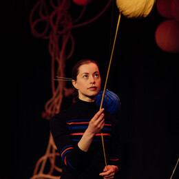 A performer holding wool from a giant ball of wool