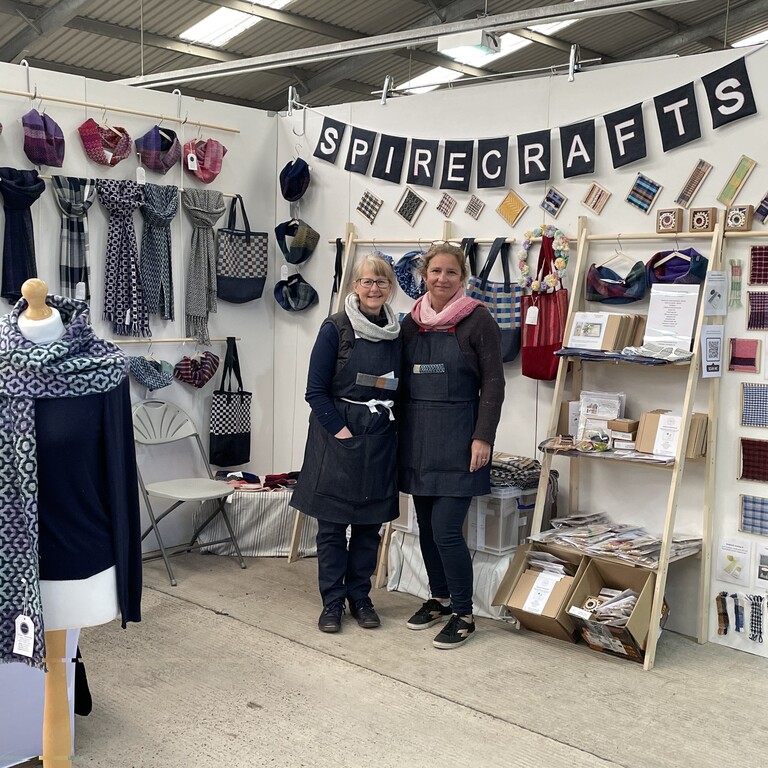 stall at a fair with scarves on display and two ladies standing