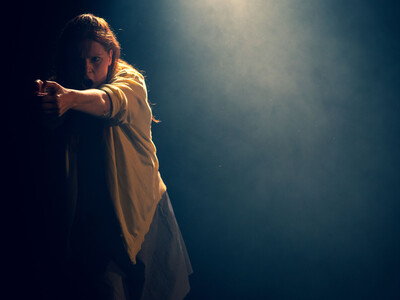 Woman dressed in yellow cardigan stretching out her left arm